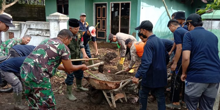 Puluhan warga LDII Kabupaten Banyuwangi bersama dengan anggota TNI-Polri bergotong-royong membersihkan lumpur dan sampah, yang menumpuk di Kelurahan Sobo, Kabupaten Banyuwangi, Jawa Timur (19/10). Foto: LINES.