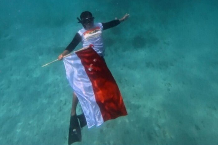 Pemuda LDII Bali mengibarkan bendera bawah laut di Laut Padang Bai. Foto: LINES.